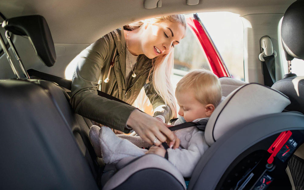 Mamma Allaccia la Cintura di Sicurezza al Bambino sul Seggiolino